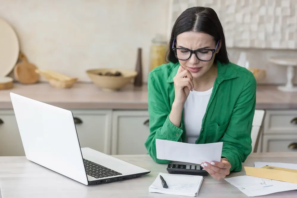 A property owner at a kitchen table comparing a statement against a laptop