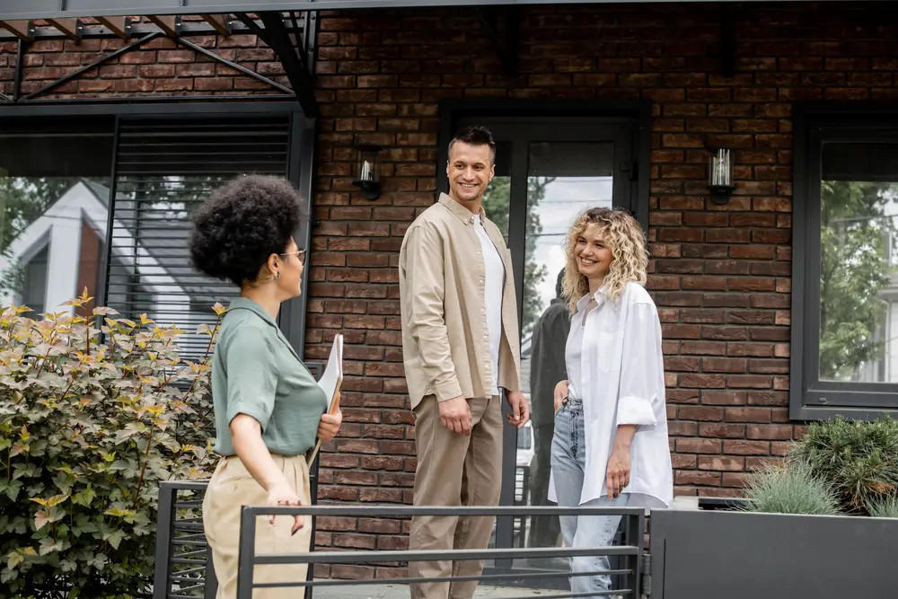 A leasing agent showing a couple around the outside of a rental home