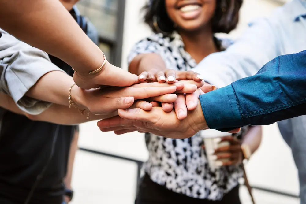 Colleagues putting their hands together in the middle of a group